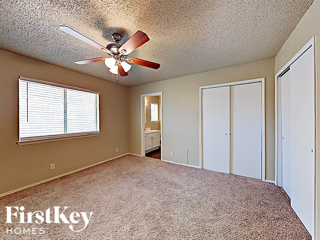 A room with a ceiling fan and a window with blinds.