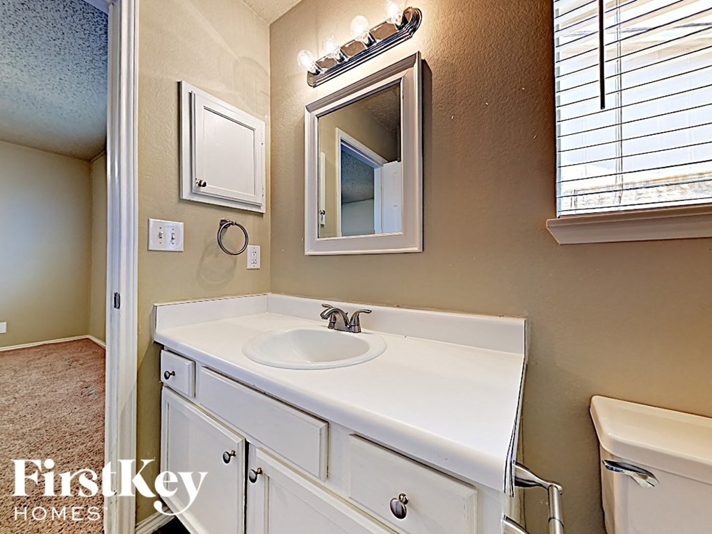A bathroom with a sink, mirror, and a towel rack.