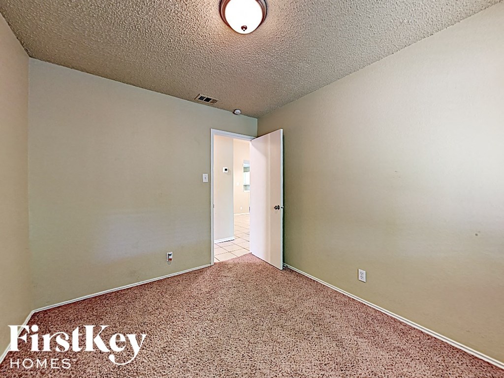 A room with a carpeted floor and a doorway leading to another room.