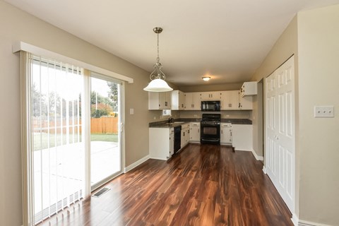 A kitchen with white cabinets and a wooden floor.