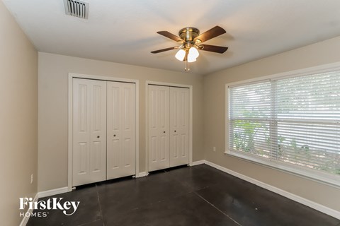 the master bedroom has a large window and a ceiling fan