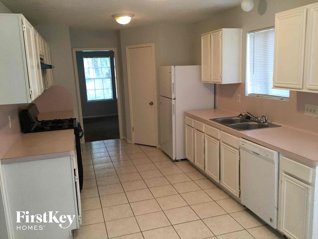 a kitchen with white cabinets and a sink and a refrigerator