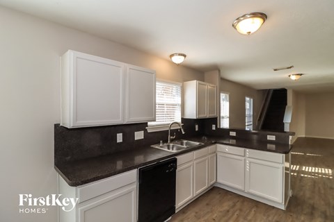 a kitchen with white cabinets and black counter tops and a sink