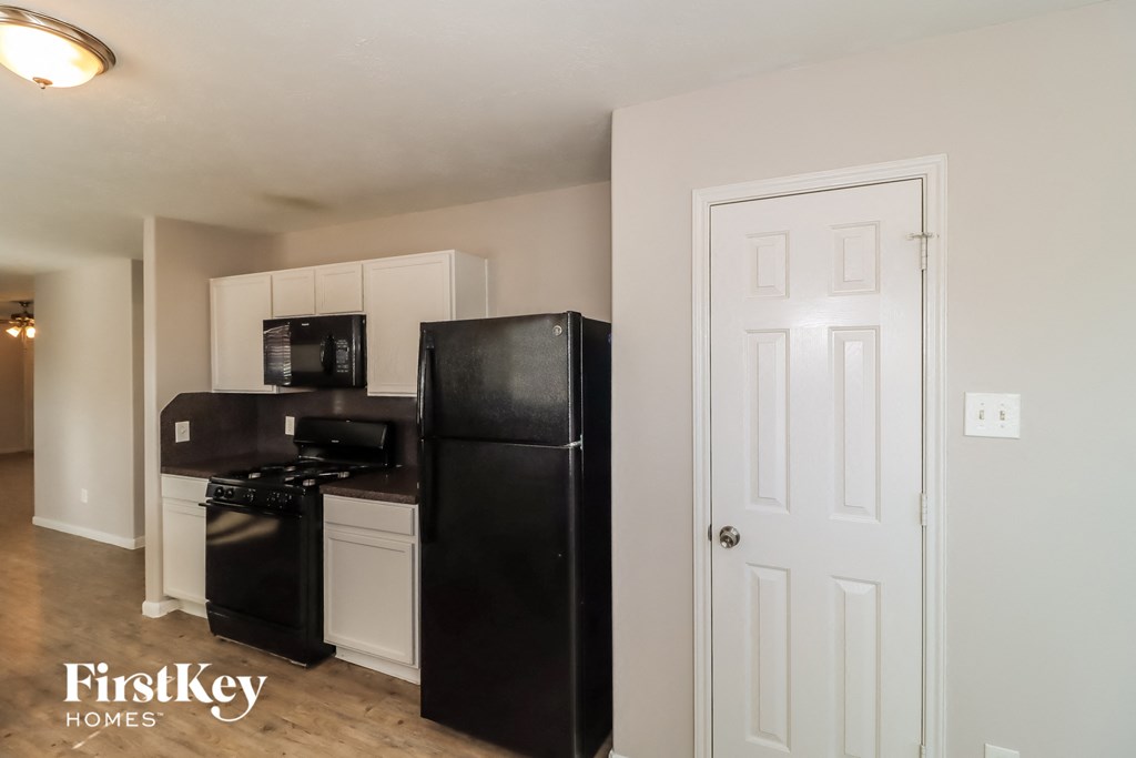 a kitchen with a black refrigerator and a white door