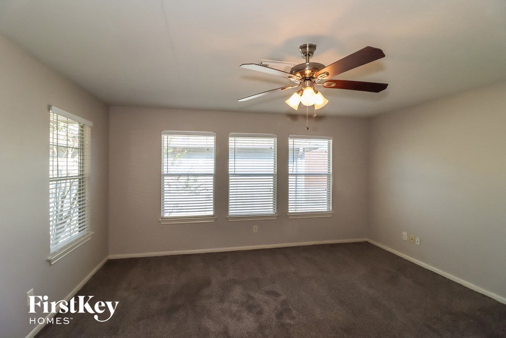 a living room with a ceiling fan and three windows
