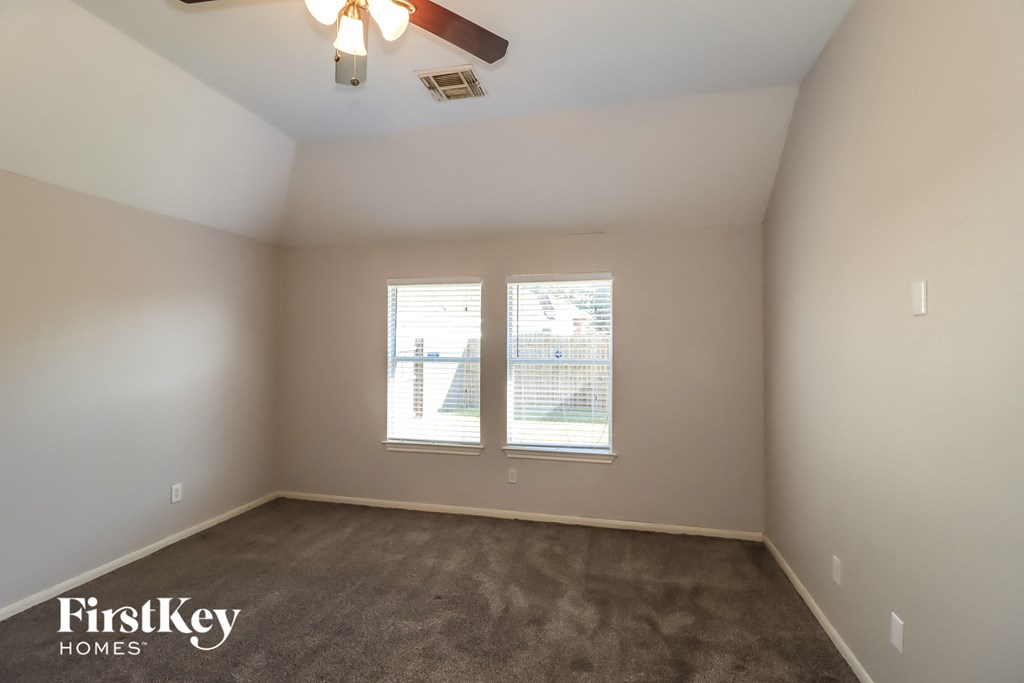 a empty room with a ceiling fan and two windows