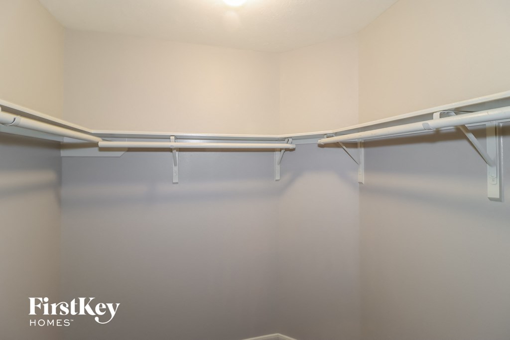 a walk in closet with empty shelves and a white wall