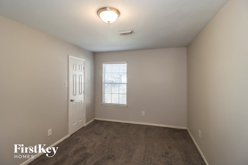 a bedroom with a carpeted floor and a white door and window