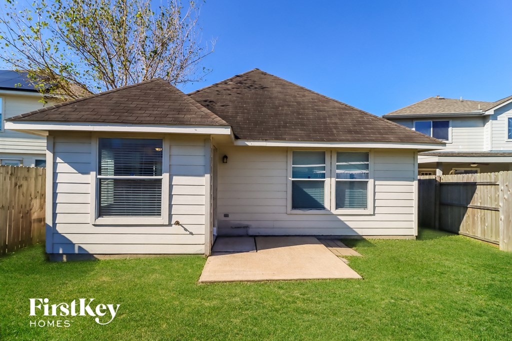 a small white house in a backyard with a lawn and a fence