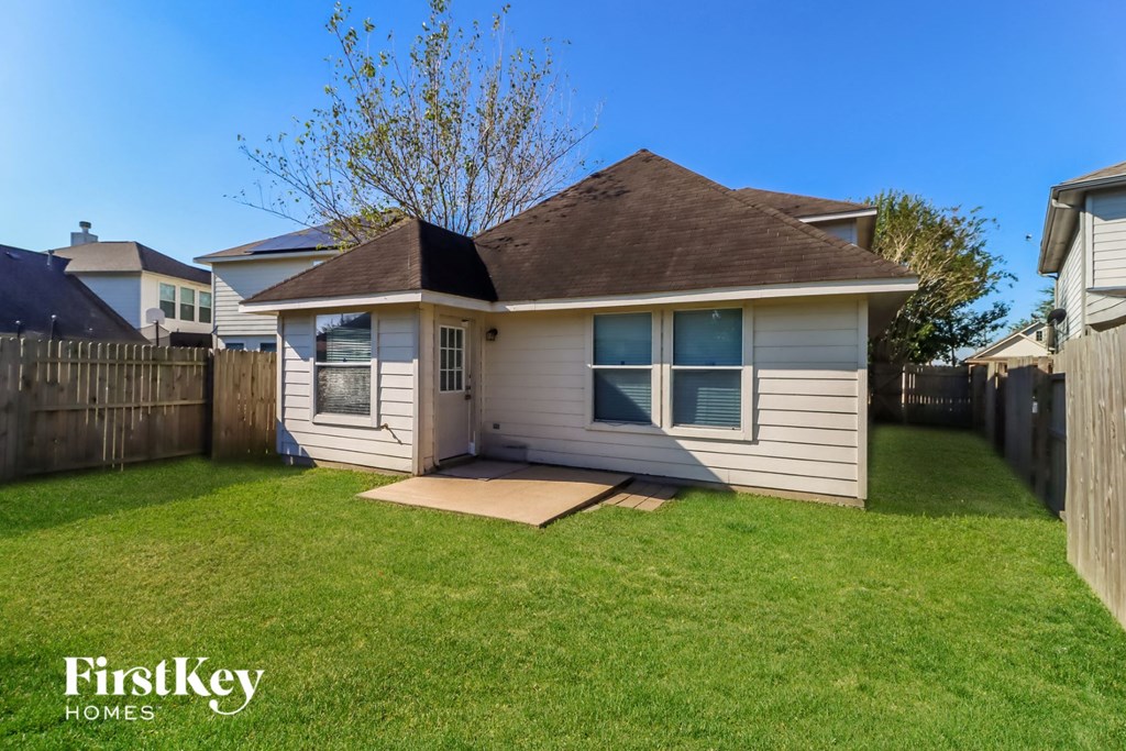 a small white house in a backyard with a lawn and a fence