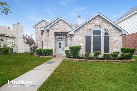 the front of a brick house with a white door and a lawn