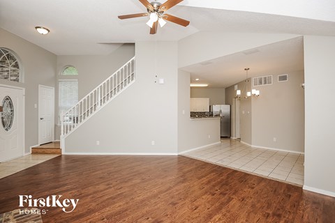 an empty living room with a ceiling fan and a staircase