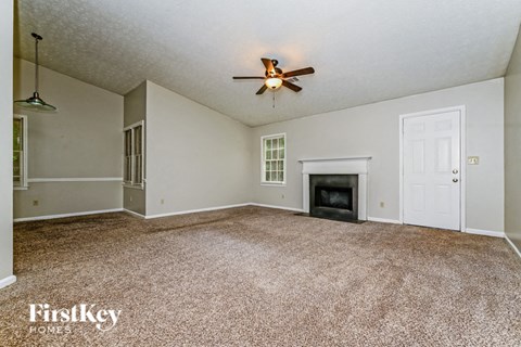 A spacious living room with a fireplace and a ceiling fan.