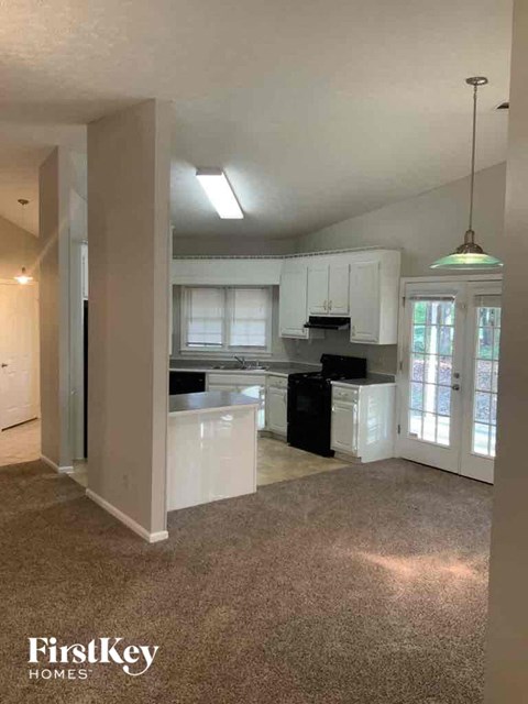 A kitchen with white cabinets and a black fridge.