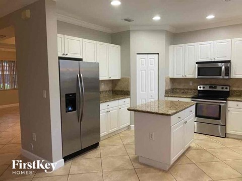 A kitchen with a refrigerator, microwave, oven and cabinets.