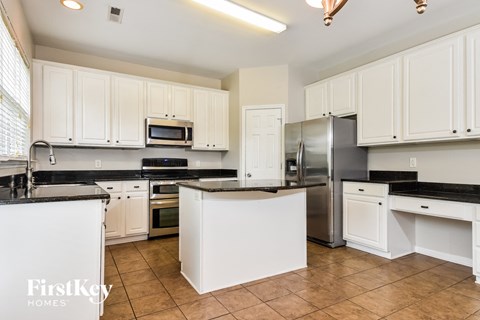 A kitchen with white cabinets and a black counter top.