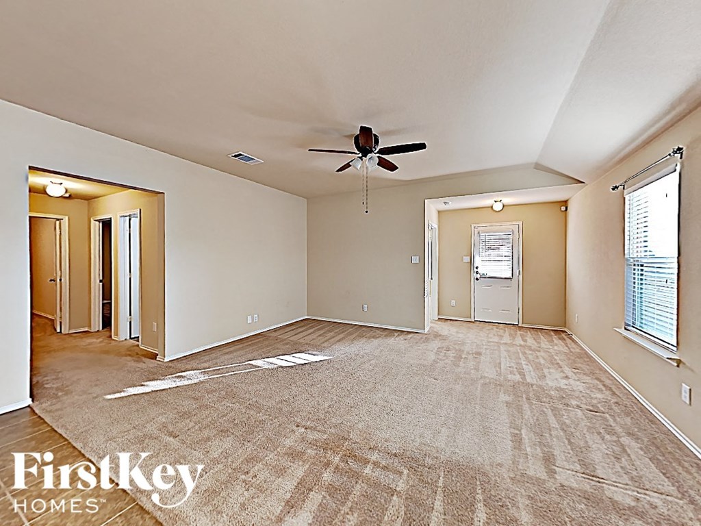 A spacious room with a carpeted floor and a ceiling fan.
