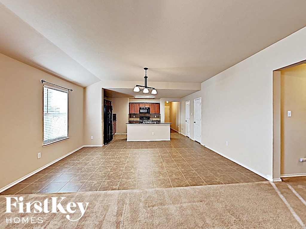 A spacious living room with a kitchen in the background.