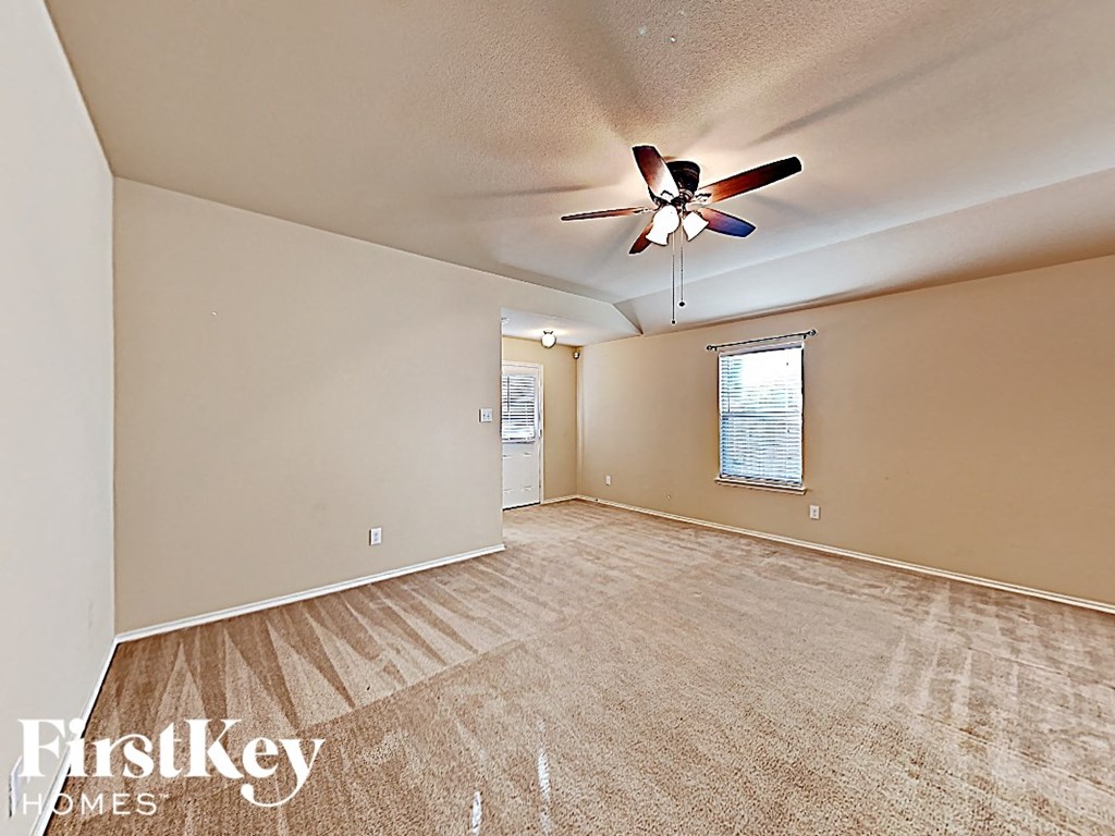 A room with a fan and a window with blinds.