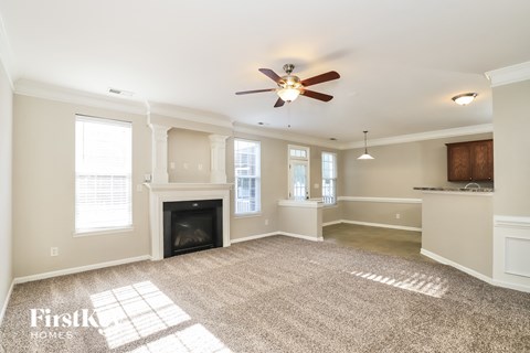 A spacious living room with a fireplace and a ceiling fan.