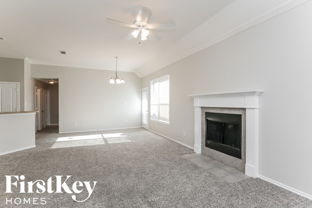 an empty living room with a fireplace and a ceiling fan