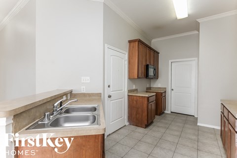 a kitchen with a sink and cabinets and a door to the living room