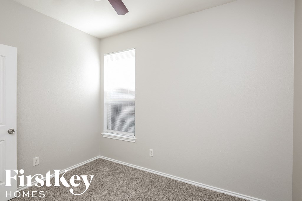 a bedroom with a window and a carpeted floor