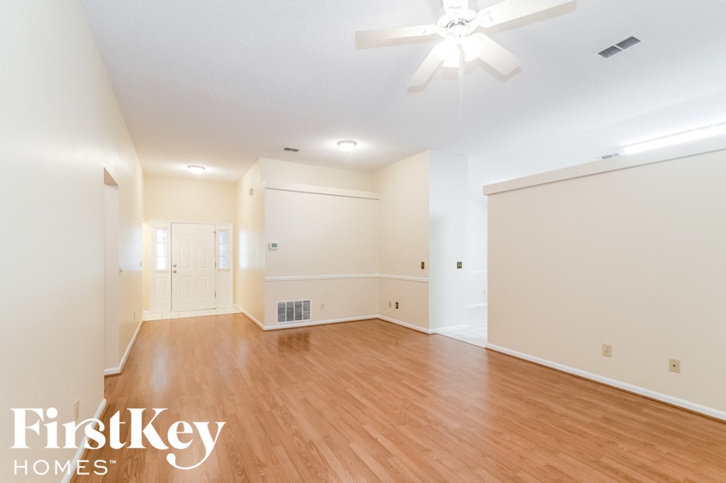 A spacious room with wooden floors and a ceiling fan.