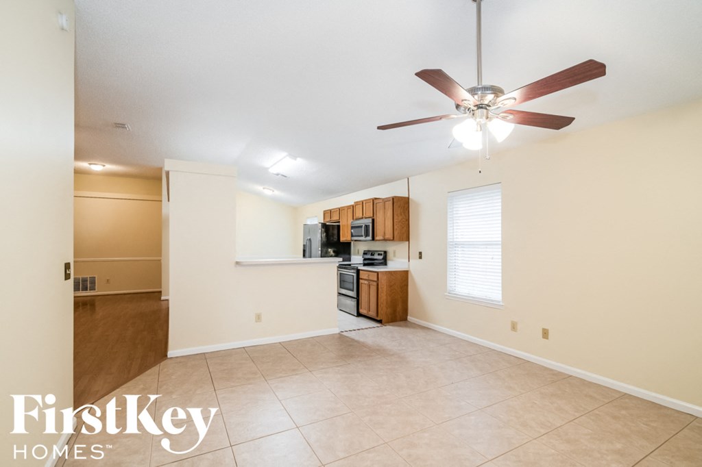 A spacious room with a fan and a kitchenette.