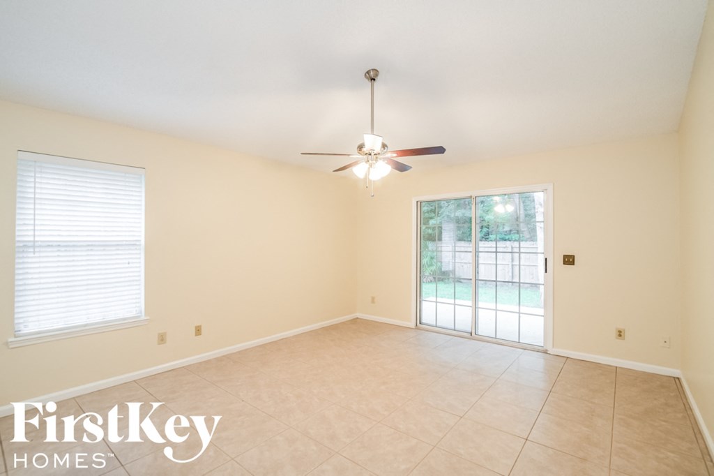 A room with a ceiling fan and sliding glass doors.