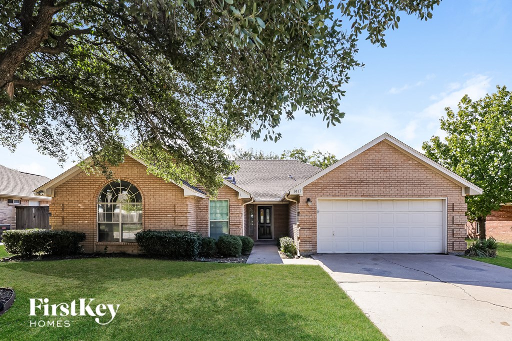 A house with a garage and a tree in front of it.