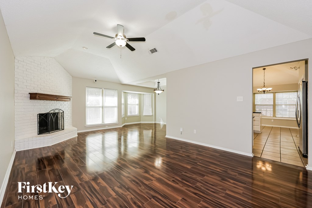 A spacious room with wooden floors and a fireplace.