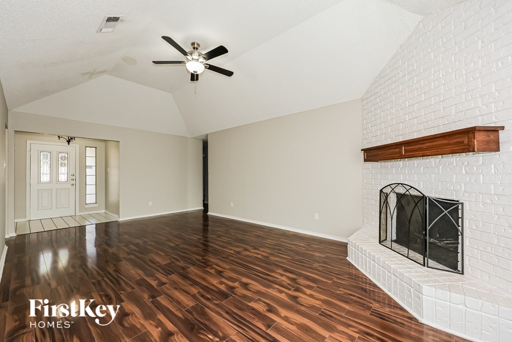 A spacious room with a fireplace and wooden flooring.
