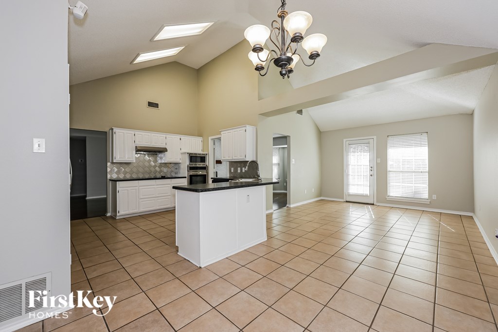 A kitchen with a white island and a chandelier.