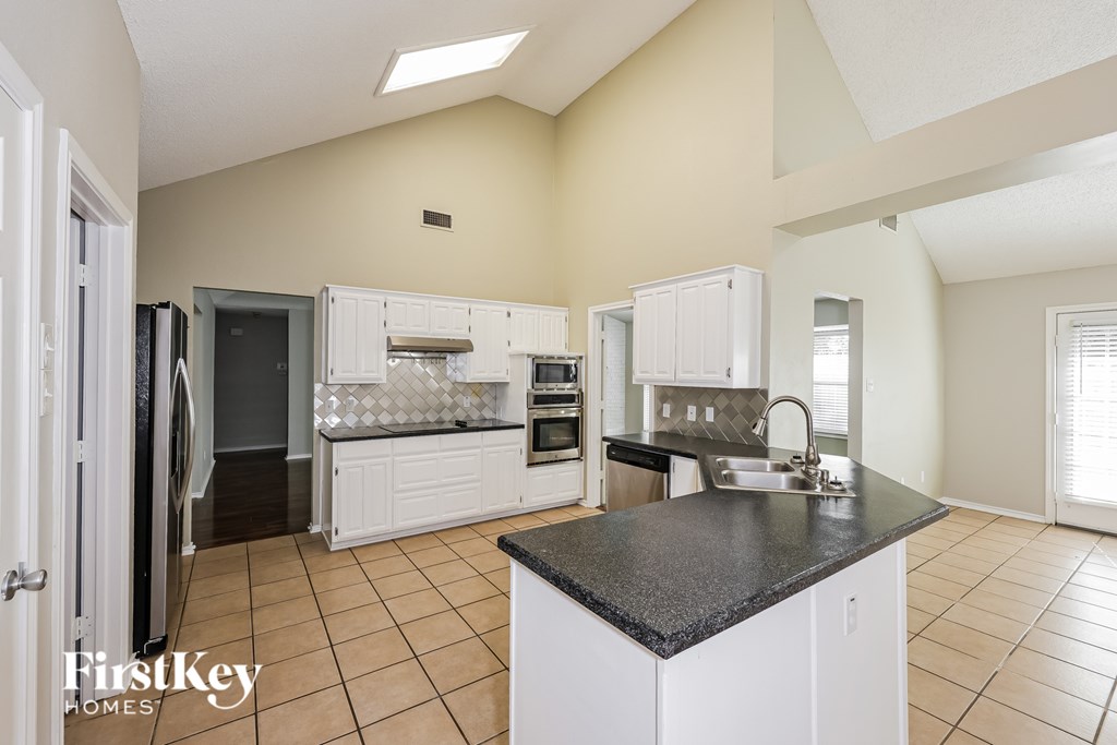 A kitchen with white cabinets and a black countertop.