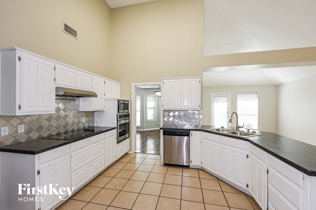 A kitchen with white cabinets and black countertops.