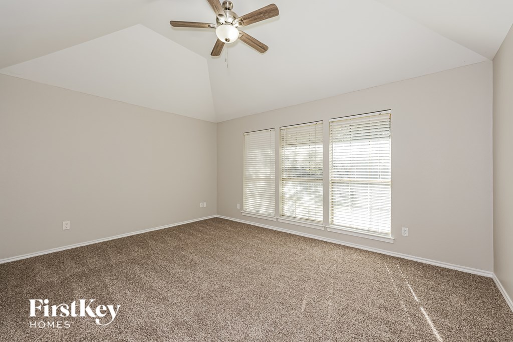 A room with a ceiling fan and carpeted floor.