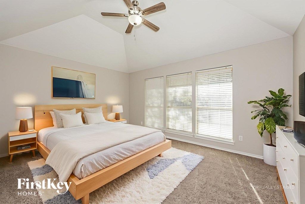 A bedroom with a bed, a ceiling fan, and a rug.