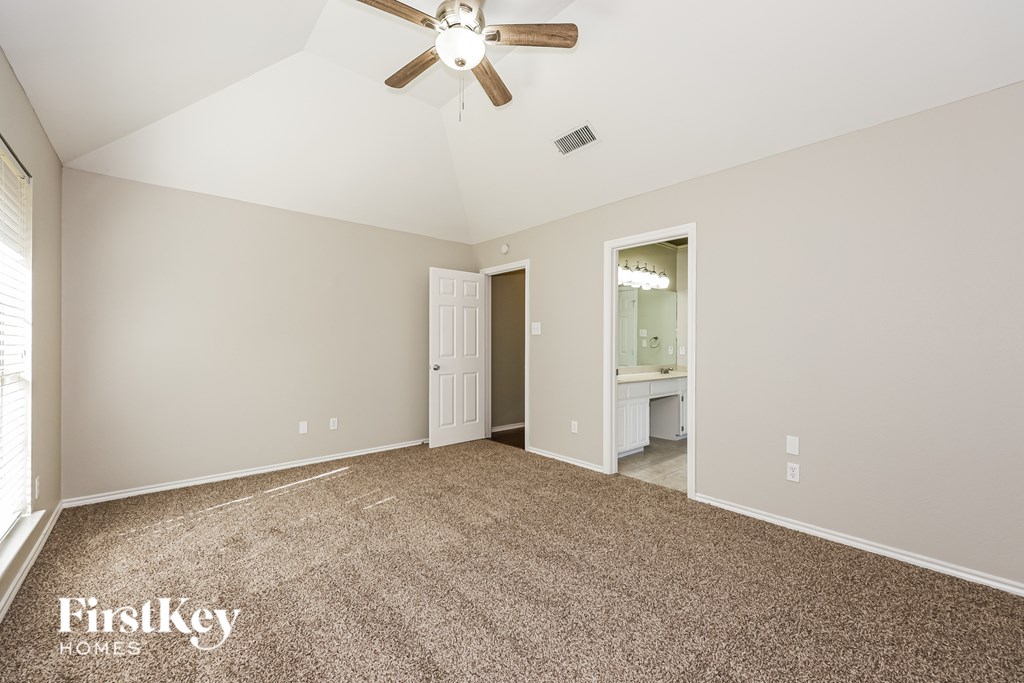 A spacious room with a ceiling fan and a carpeted floor.