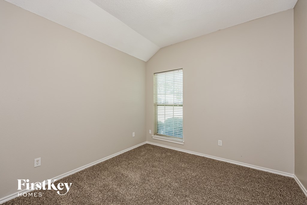 A room with a carpeted floor and a window with blinds.