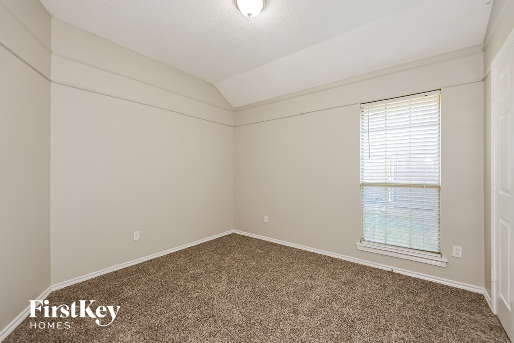 A room with a carpeted floor and a window with blinds.