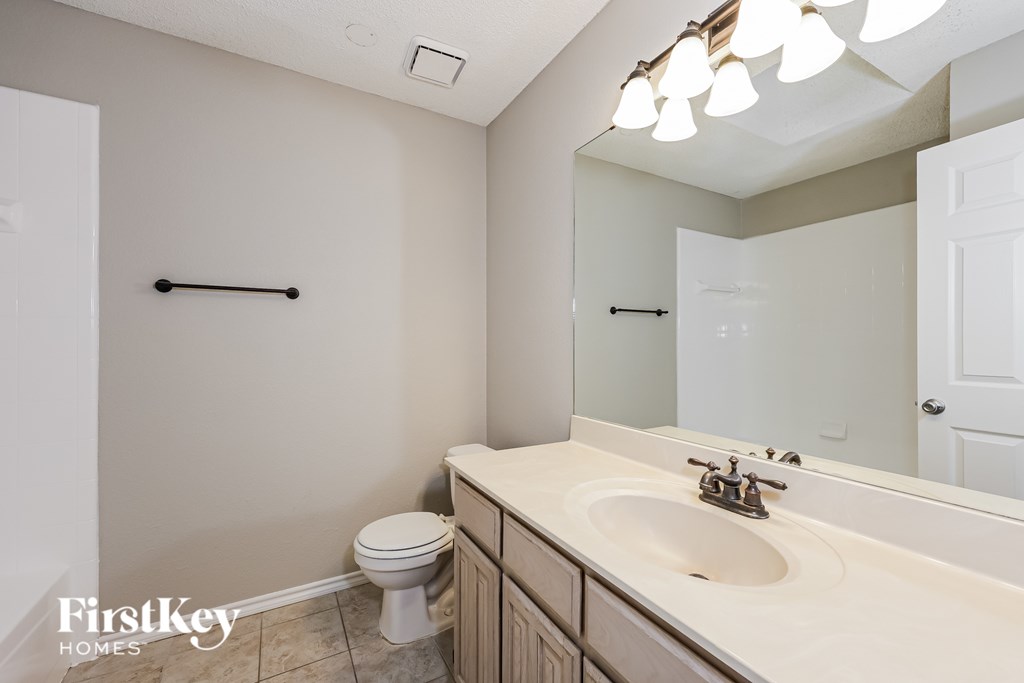 A bathroom with a toilet, sink, and mirror.