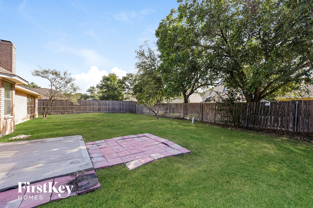 A backyard with a pink tarp on the ground.