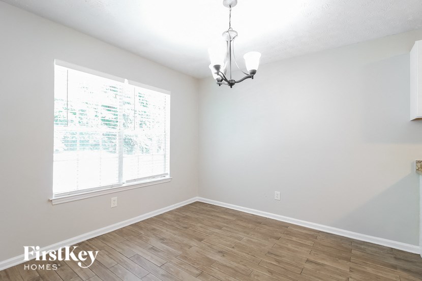 the living room of an empty house with wood flooring and a large window