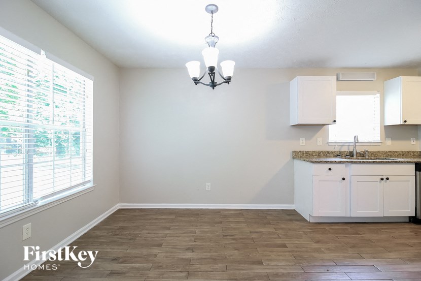 an empty kitchen with white cabinets and a large window