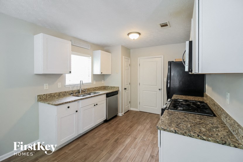 a kitchen with white cabinets and granite counter tops and a black stove and refrigerator