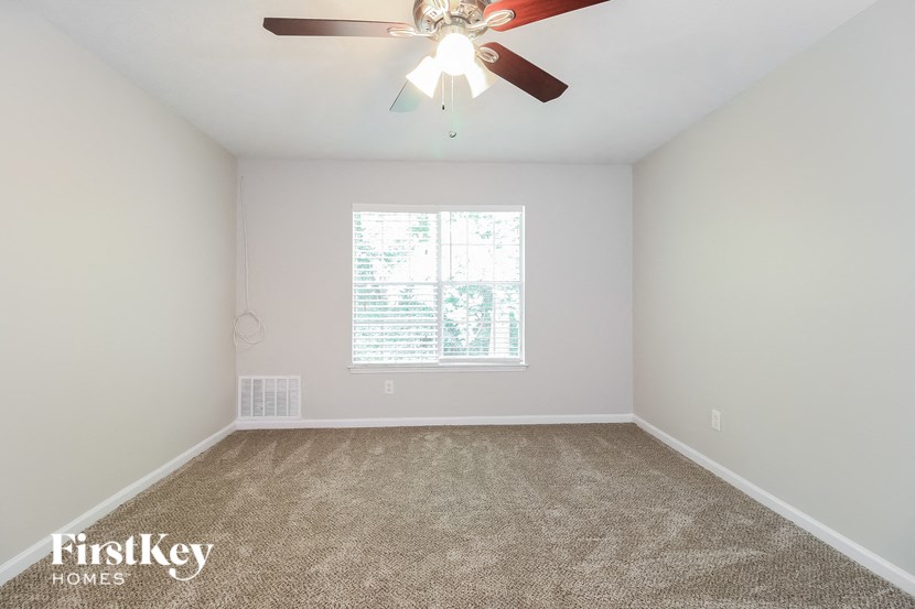 the spacious living room with carpet and a ceiling fan