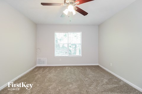 the spacious living room with carpet and a ceiling fan
