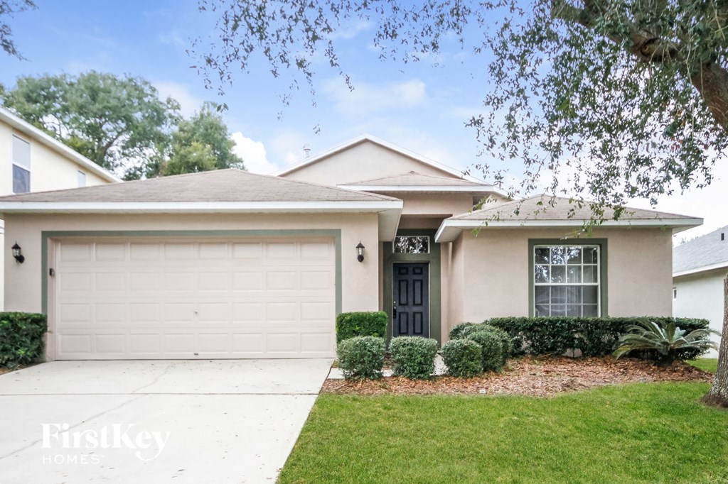 a beige house with a garage door and a lawn