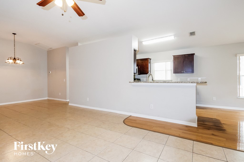 an empty living room with a kitchen and a wooden floor
